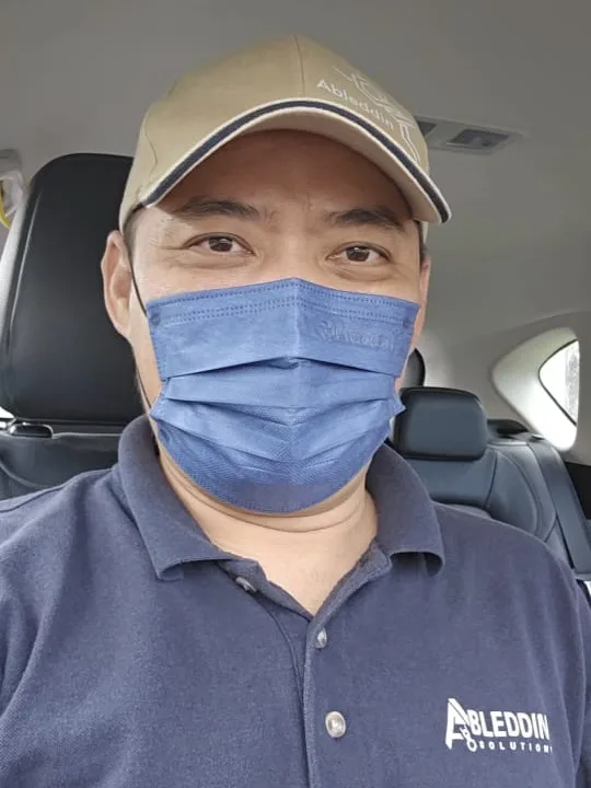 Alan 戴着 Ableddin 的帽子和口罩,穿 Ableddin Solutions 深蓝色 Polo 衫,在车上自拍